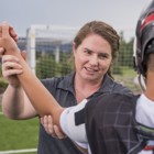 Athletic trainer helps a lacrosse player stretch his arm.