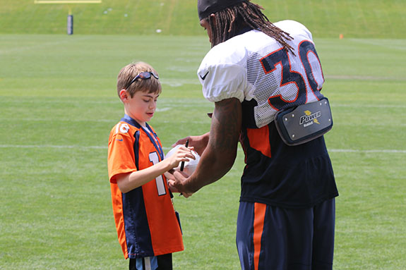 Children's Hospital Colorado Junior Reporter Braden Roome gets an autograph from a Denver Broncos player.