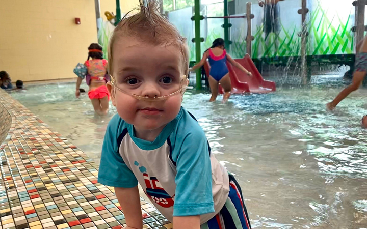 Young toddler with oxygen playing in indoor pool