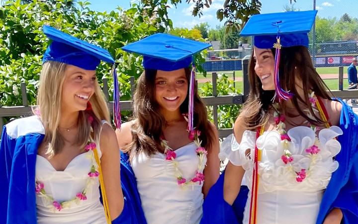 Three girls smiling in graduation caps and gowns