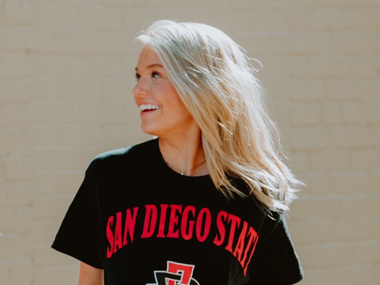 A girl in a San Diego State shirt smiling