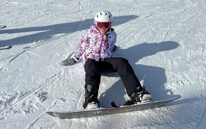 Kendall sits on a run while snowboarding.