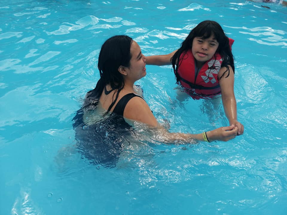 A camper and her counselor swim in the heated pool.