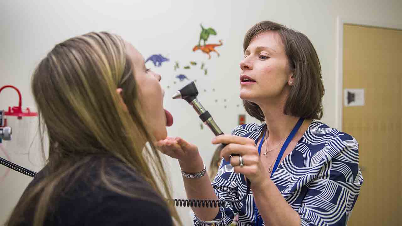 A provider looks into a teenage girl's mouth