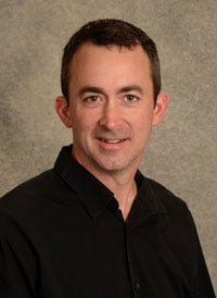 A headshot of heart perfusionist Brian Mejak who has short dark brown hair and is wearing a black polo.