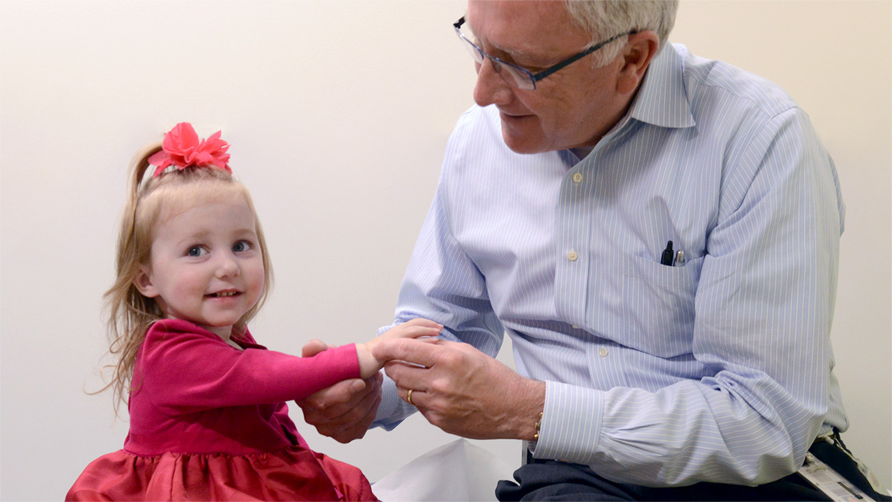 Dr. Frank Scott, Chief of Hand Wrist & Elbow at Children's Hospital Colorado, examines a young girl's hand and wrist.