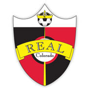 A logo of a shield that has a soccer ball with a yellow crown at the top on a white background and a yellow ribbon that says REAL across a red and black checkered background, and there's a white circle in the middle that says Colorado below the ribbon.