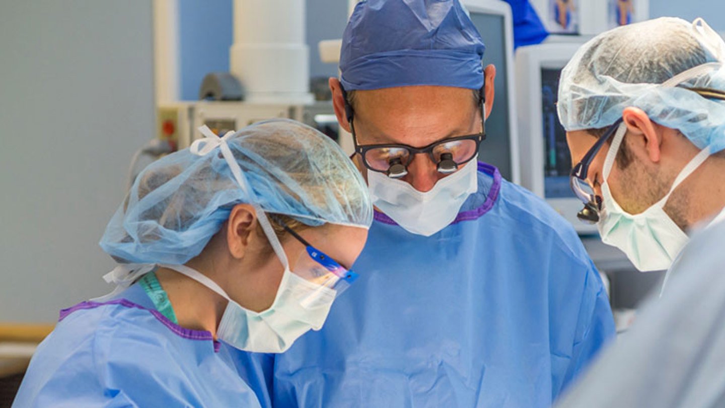 Dr. Duncan Wilcox, Surgeon-in-Chief, performing surgery with other healthcare providers in the operating room 