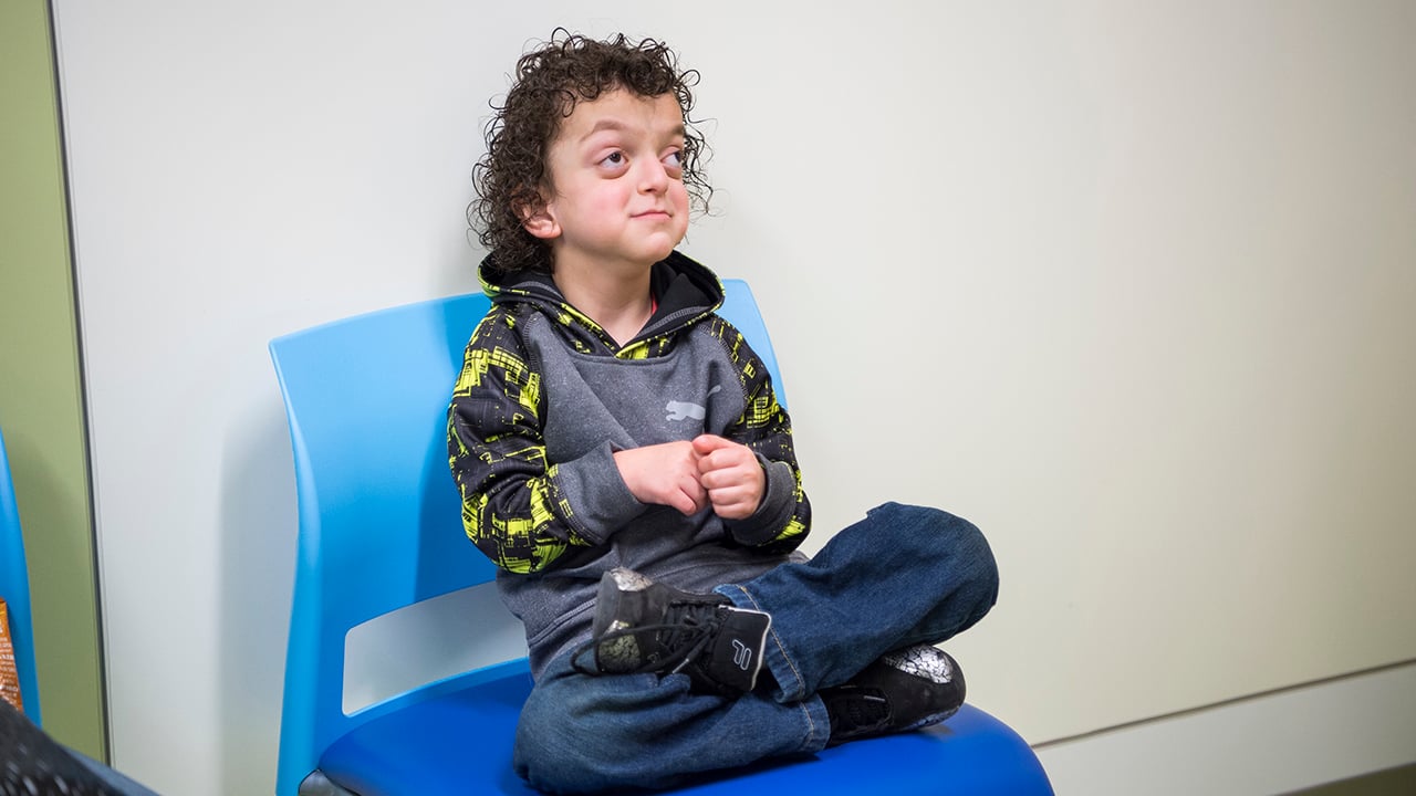 A craniofacial patient sits in a blue chair