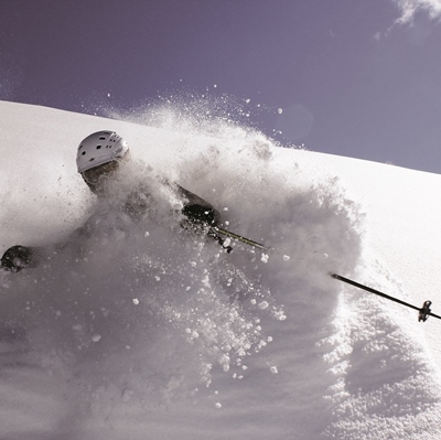 A kid skis down a mountain wearing a helmet.