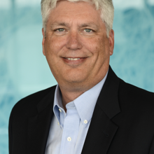 Headshot photograph of Dana Moore, vice president and CIO of Children's Hospital Colorado. He has short salt and pepper hair and is wearing a black suit jacket.