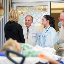 A patient is out of focus in the foreground as the medical providers in focus in the background speak to each other.