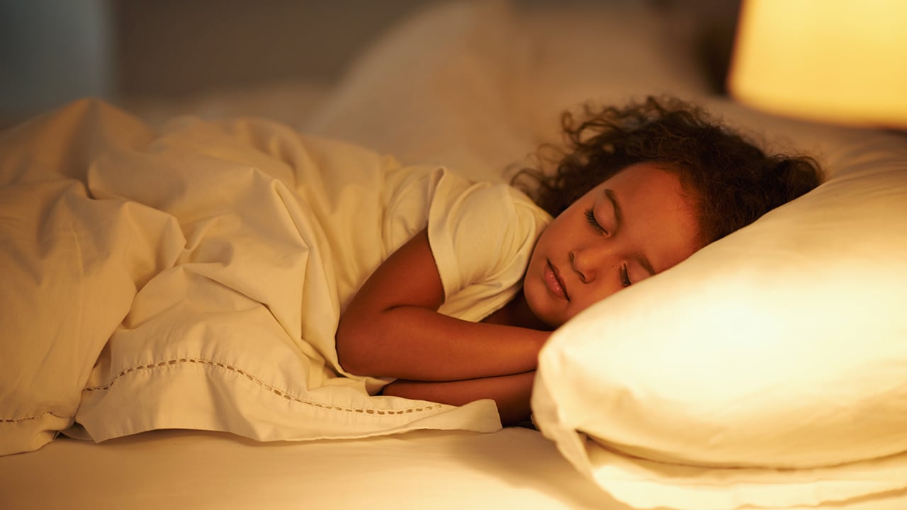 A young girl sleeps in a bed.