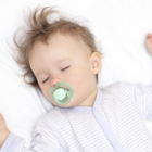 An infant sleeps on their back in a crib