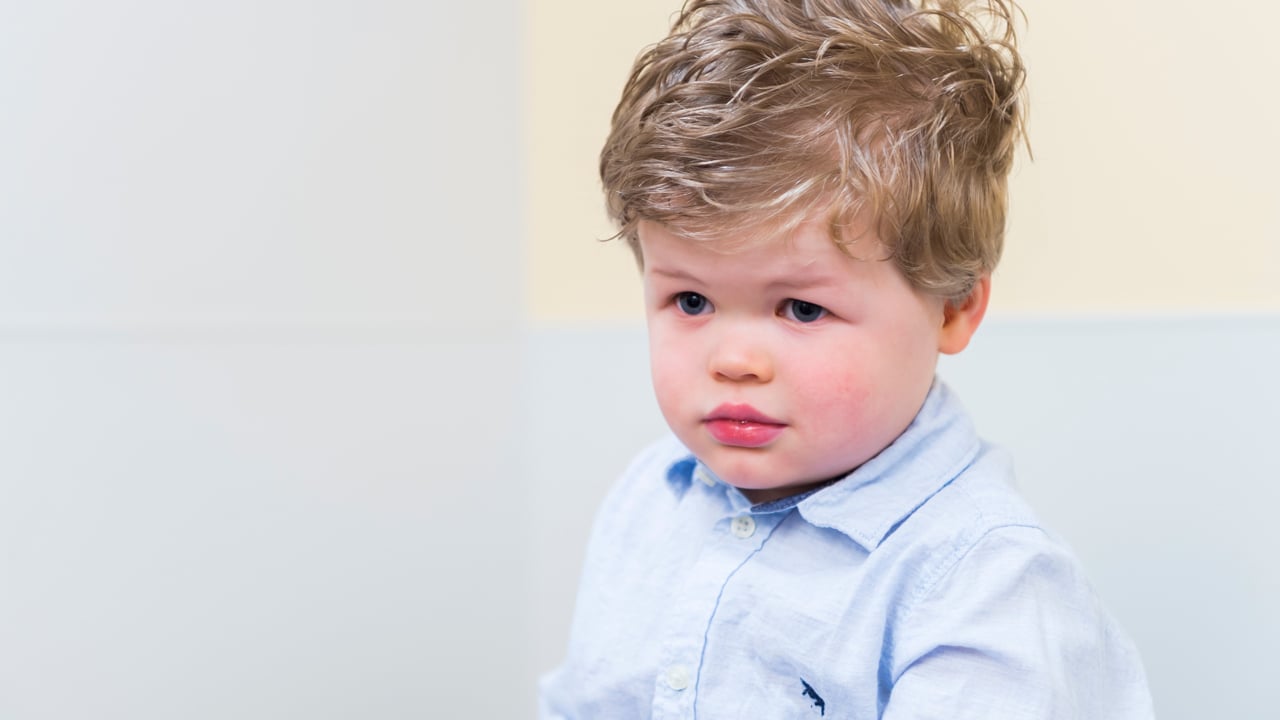 A toddler boy looks sad