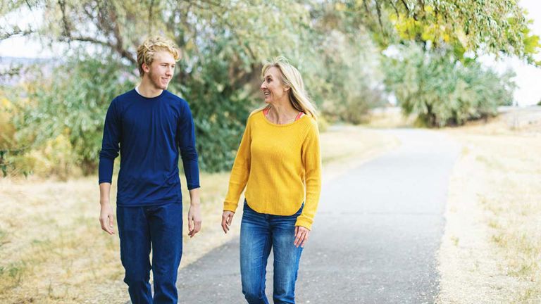 A mom and her teenage son have a heart-to-heart while walking outdoors.