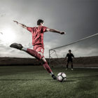 A soccer player starts to kick a ball toward the goal.