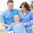 A family with a mom, dad and daughter wearing light blue and the girl holding a soccer ball.
