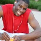 A teenage athlete wearing headphones and peeling an orange.