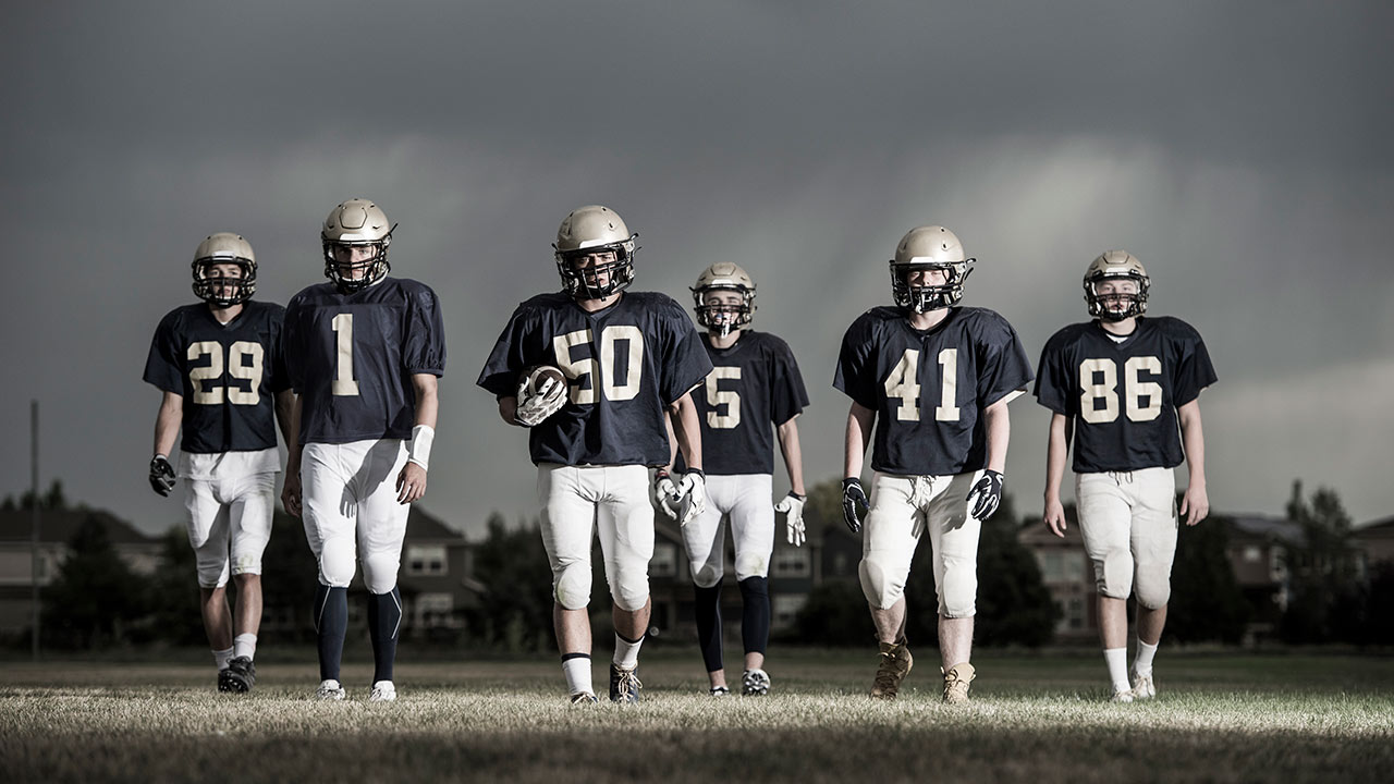 A team of high school football players walk across the field.
