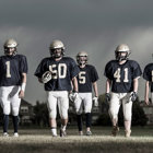 A team of high school football players walk across the field.