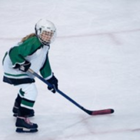 A girl hockey player skates on the ice with her stick.