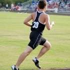A teenage boy in a black uniform runs on a track.