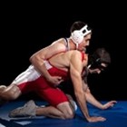Two teenage boys wrestle on a wrestling mat.