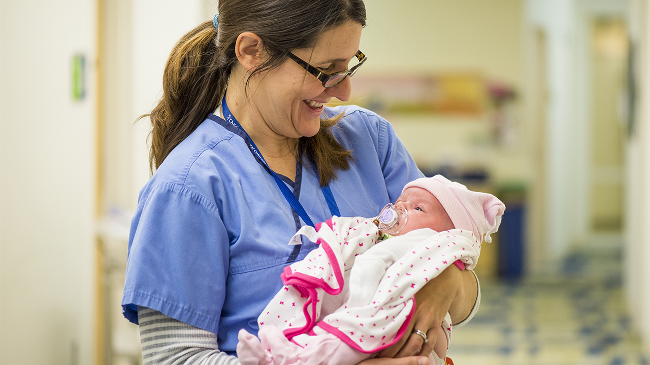 A Children's Colorado caregiver holding a newborn baby girl