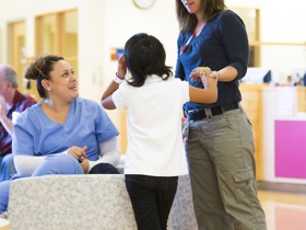 Dr. Jean Mulcahy-Levy helps a kid stand up while a woman in scrubs watches.
