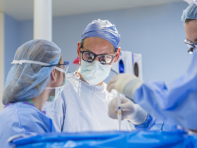 This is a picture of a surgeon performing surgery in the OR with three other healthcare professionals. 