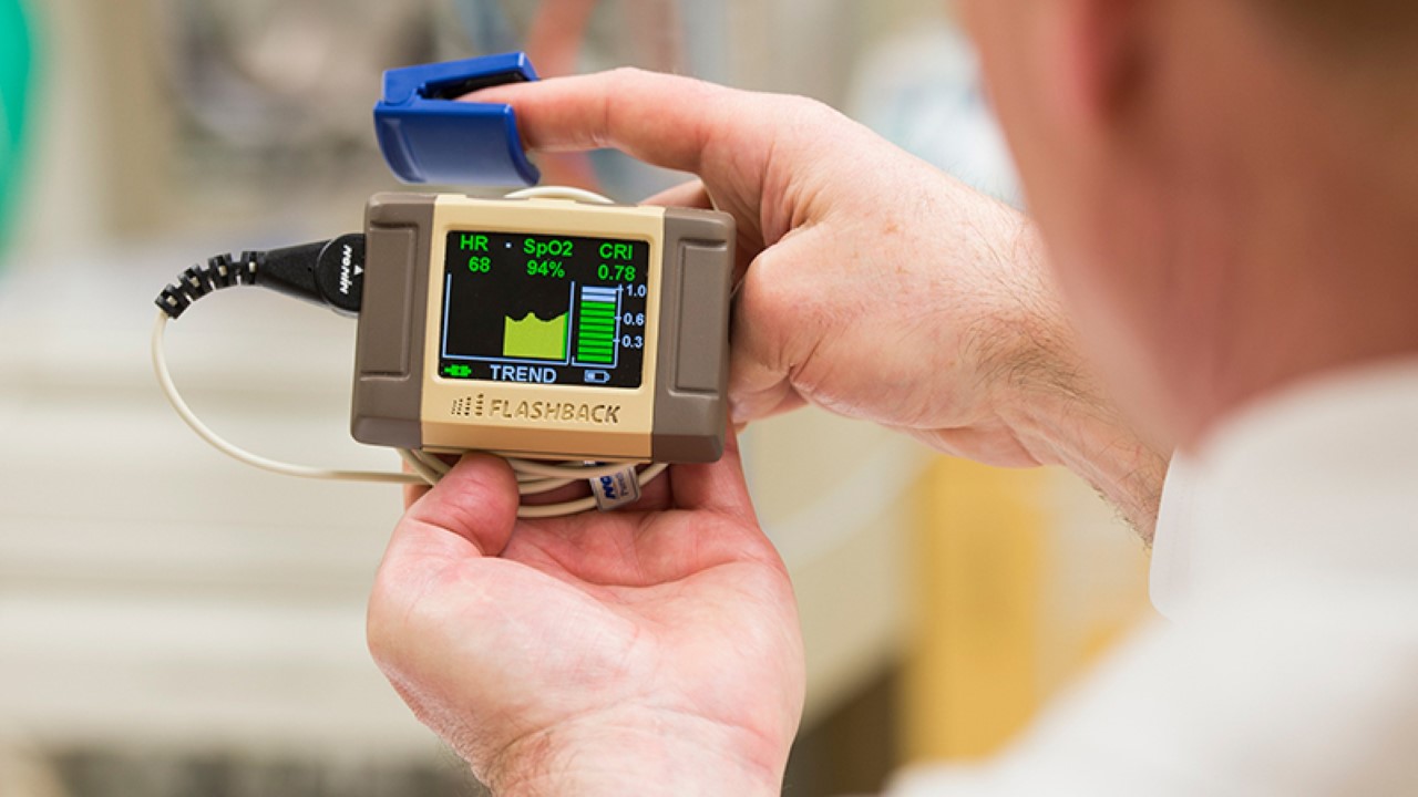 Dr. Moulton holds a small robot device showing pressure fluctuations of a beating heart.