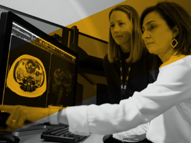 Two providers review an MRI scan on a computer screen together.
