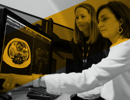 Two providers review an MRI scan on a computer screen together.