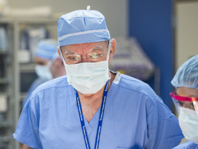 Dr. Peña close-up in scrubs with a surgical mask on preparing for surgery.